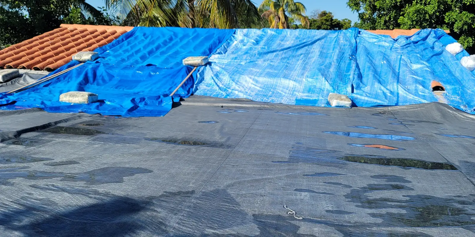 Emergency hurricane tarp deployment and sandbagged weatherproofing seal